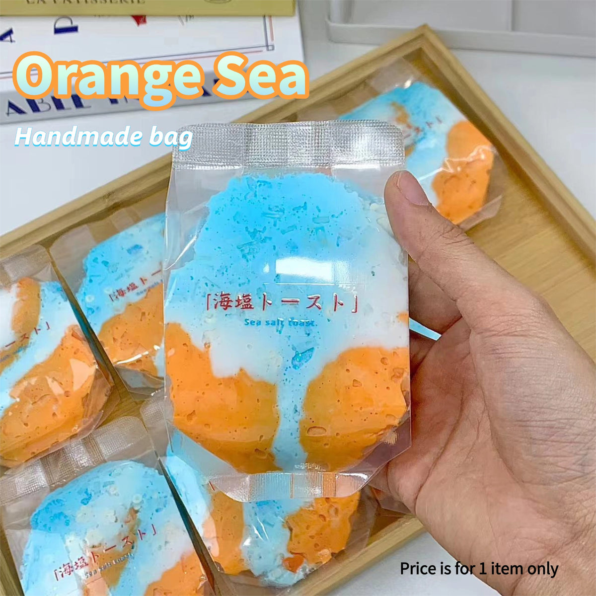 Orange Sea handmade squeeze bag held in hand showing vibrant orange and blue swirl design